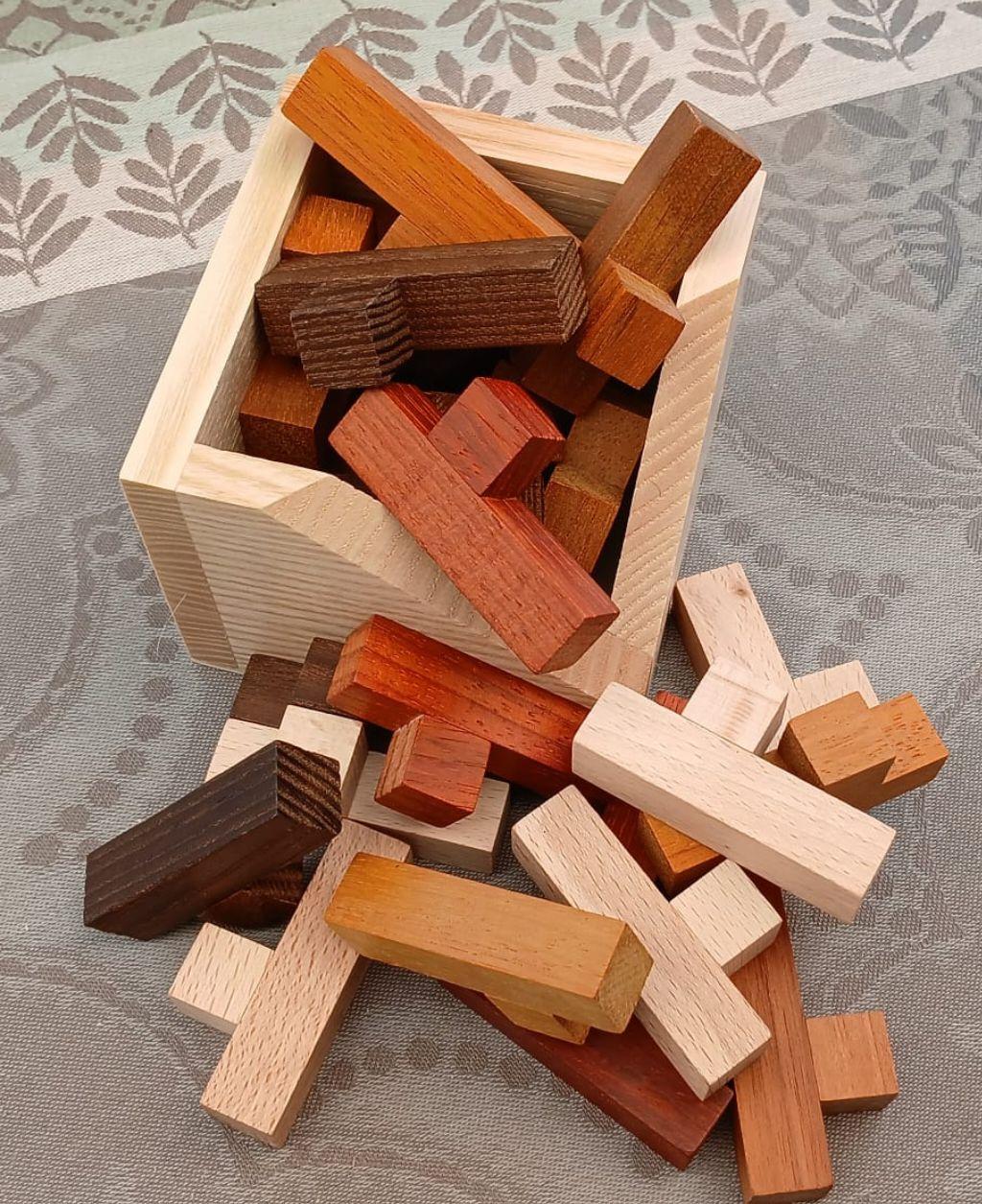 A wooden box, with a bunch of wooden pieces scattered inside it and next to it